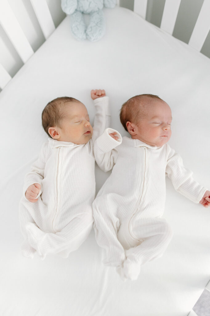 newborn twins in white onesie's stretching during indianapolis newborn photos