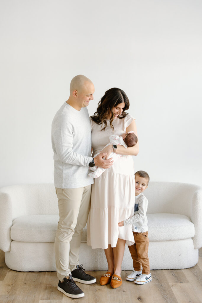 Family hugging and smiling towards newborn in studio newborn photos in indianapolis
