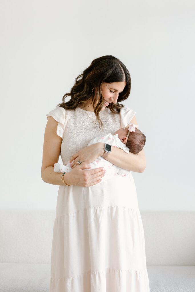 Mom smiling down towards her baby during studio newborn photos in indianapolis