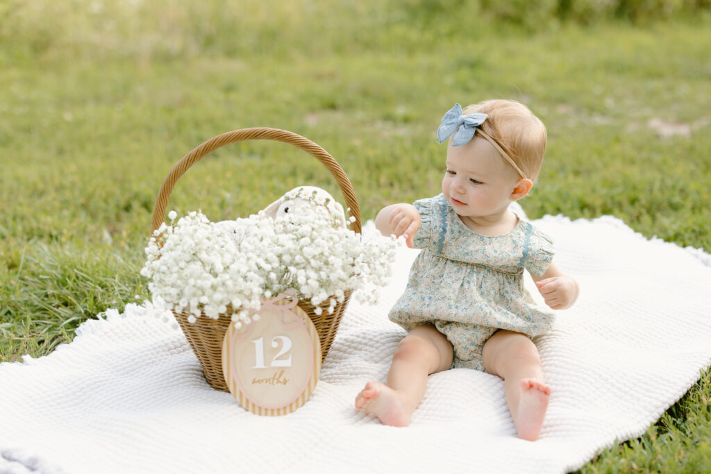 baby sitting on a blanket and playing with flowers during Indianapolis Milestone Photography session