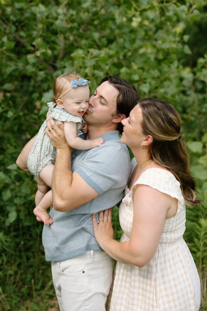 Mom and dad kissing baby girl during Indianapolis Milestone Photography session