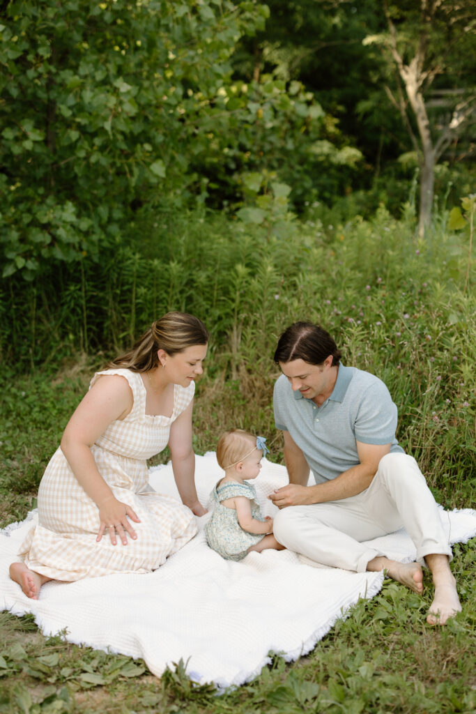 Parents sitting with baby girl on a blanket during Indianapolis Milestone Photography session