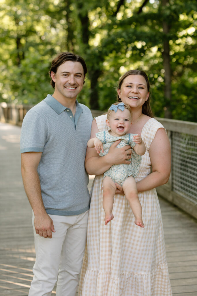 Dad and mom holding baby and smiling to camera in Indianapolis Milestone Photography session