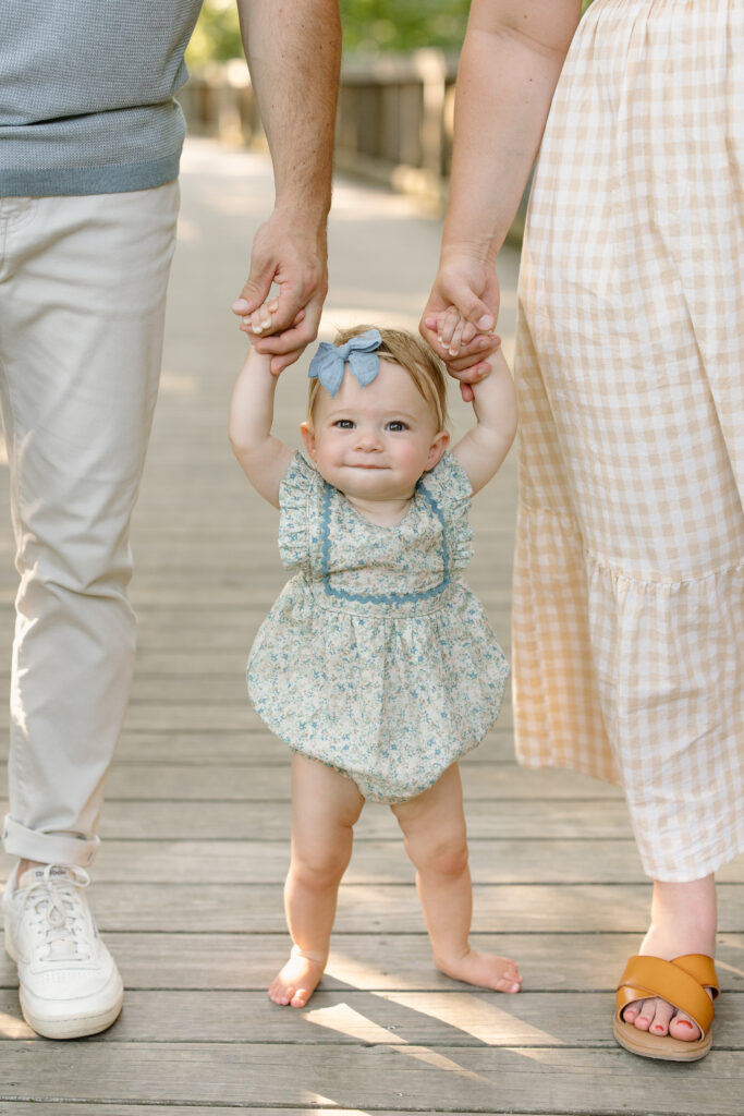 Baby holding onto parent's hands during Indianapolis Milestone Photography session