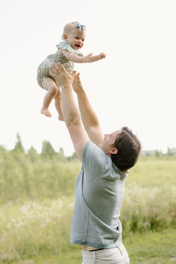 dad throwing little girl into the air during Indianapolis Milestone Photography session