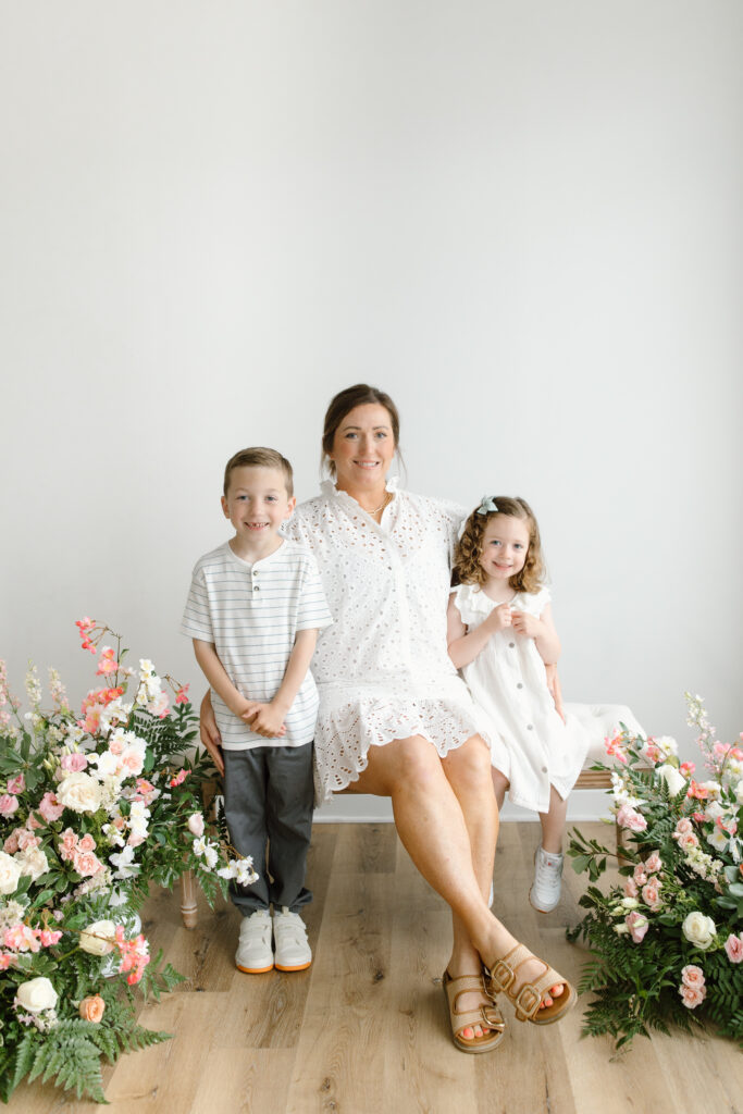 Family sitting on the bench and smiling to the camera during Mother's Day Mini Sessions at Aspiring Eden Studio in Indianapolis