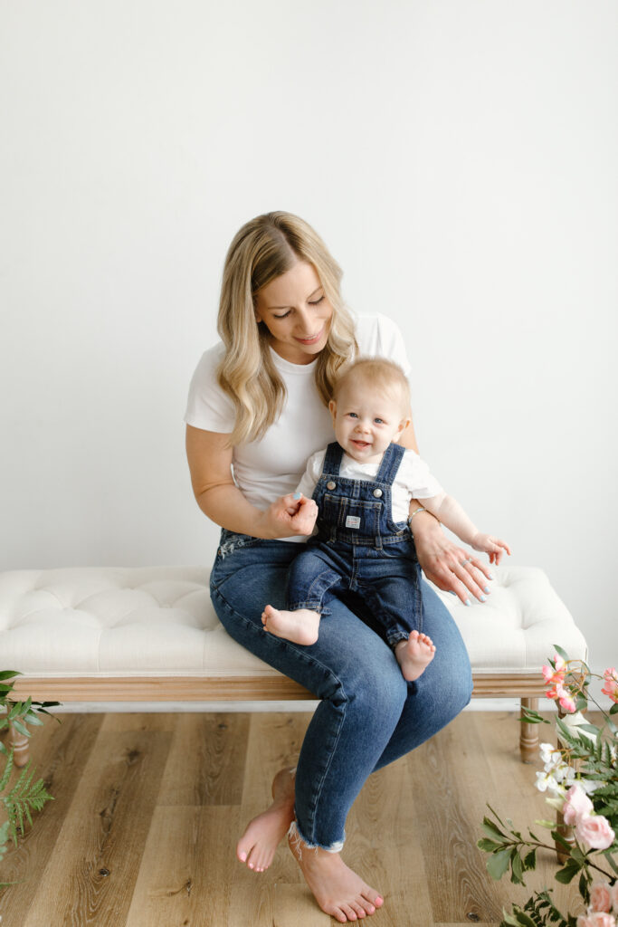 Baby laughing to camera and sitting on mom's lap during Mother's Day Mini Sessions at Aspiring Eden Studio in Indianapolis