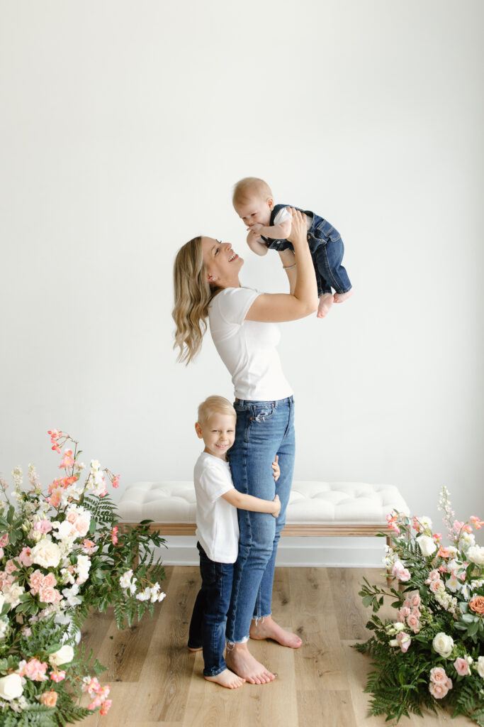 Mom lifting baby with son hugging during Mother's Day Mini Sessions at Aspiring Eden Studio in Indianapolis