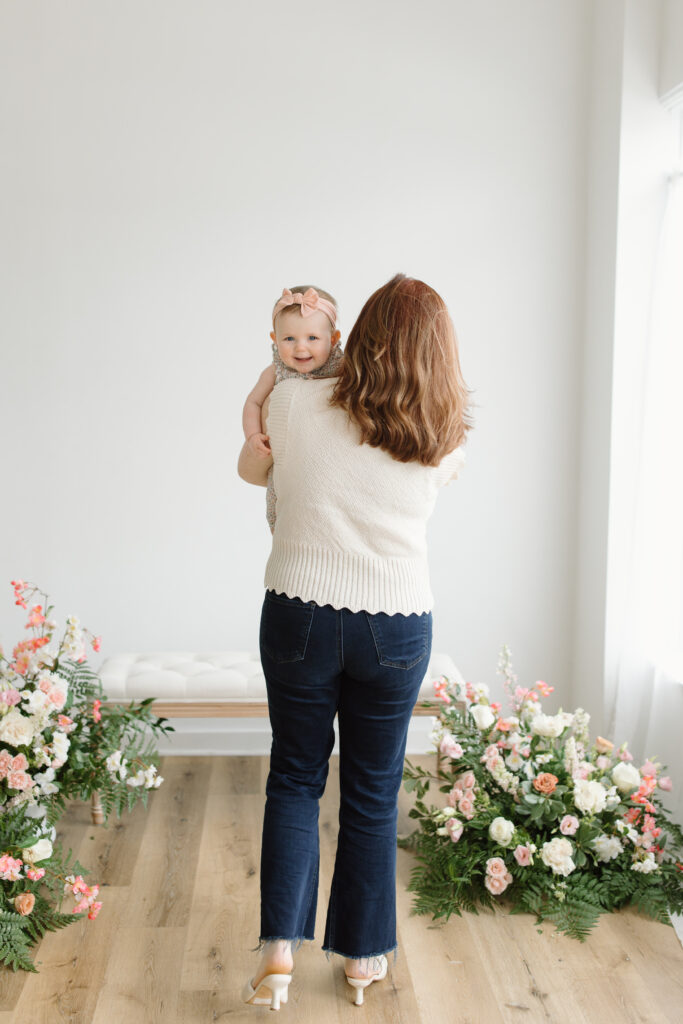 Mom walking away and baby smiling towards camera during Mother's Day Mini Sessions at Aspiring Eden Studio in Indianapolis
