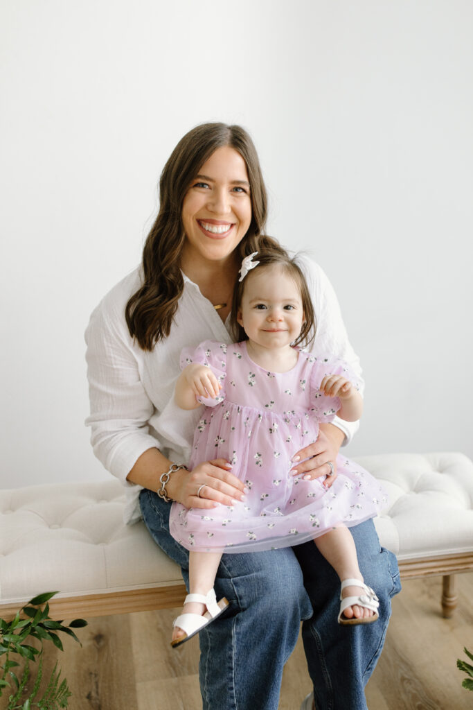 Mom smiling with daughter on her lap during Mother's Day Mini Sessions at Aspiring Eden Studio in Indianapolis