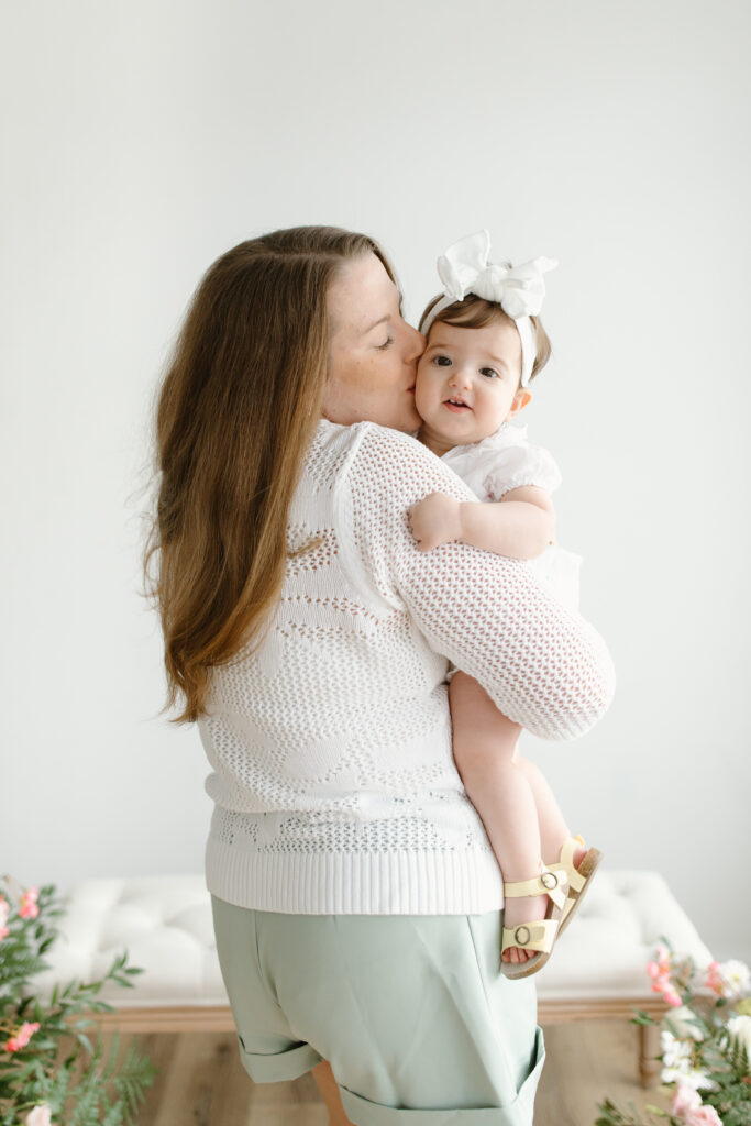 Mom kissing her daughter on the cheek during Mother's Day Mini Sessions at Aspiring Eden Studio in Indianapolis