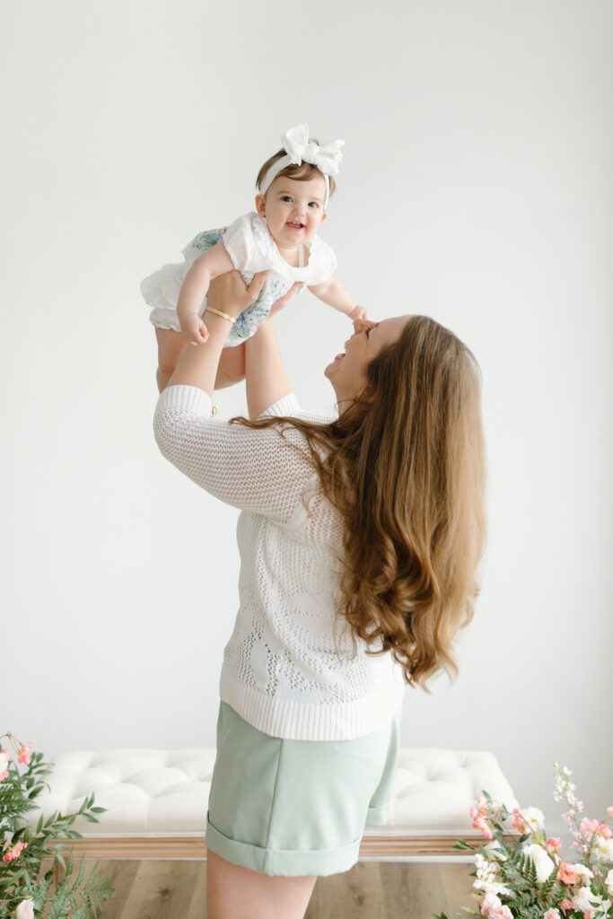 Mom lifting daughter and smiling to camera during Mother's Day Mini Sessions at Aspiring Eden Studio in Indianapolis