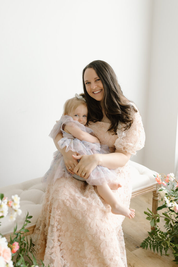 Mom holding her daughter on a bench during Mother's Day Mini Sessions at Aspiring Eden Studio in Indianapolis