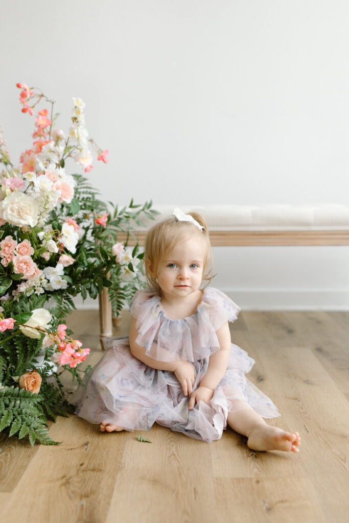 Little girl sitting next to flowers during Mother's Day Mini Sessions at Aspiring Eden Studio in Indianapolis