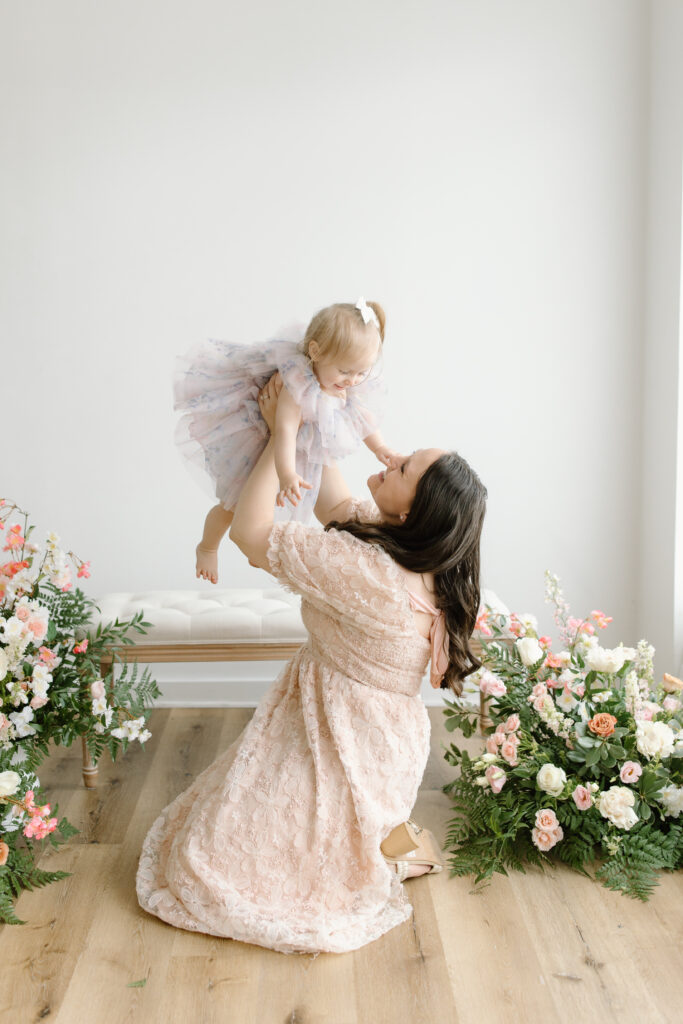 Mom lifting daughter while sitting on the floor during Mother's Day Mini Sessions at Aspiring Eden Studio in Indianapolis