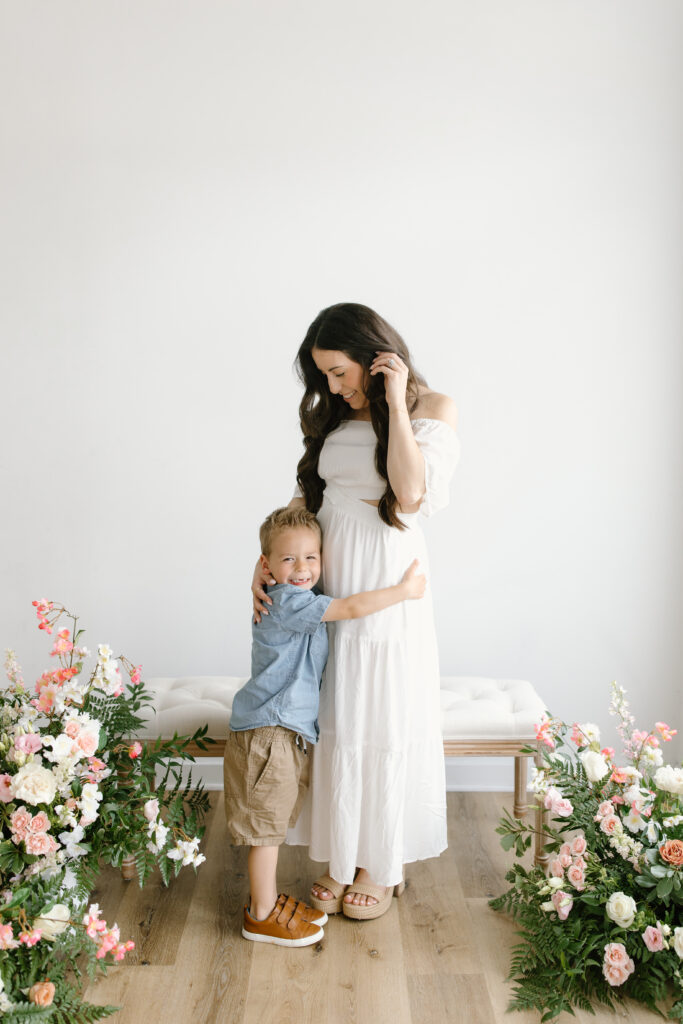 Mom smiling down towards her son while he looks at the camera during Mother's Day Mini Sessions at Aspiring Eden Studio in Indianapolis