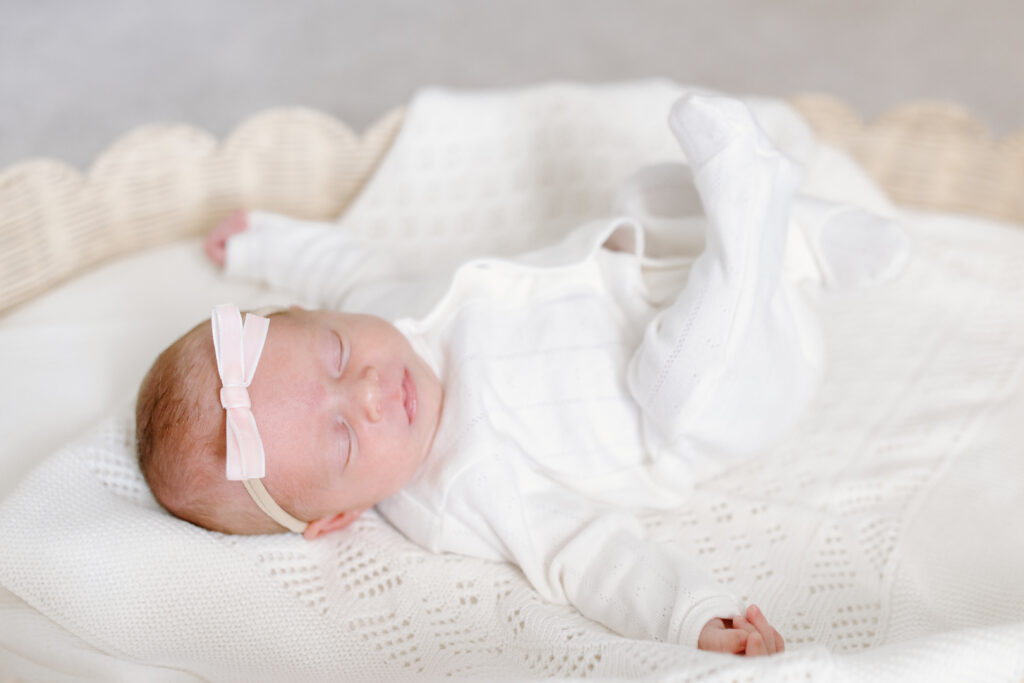 baby lying in basket with pink bow during newborn photos in Fishers, IN