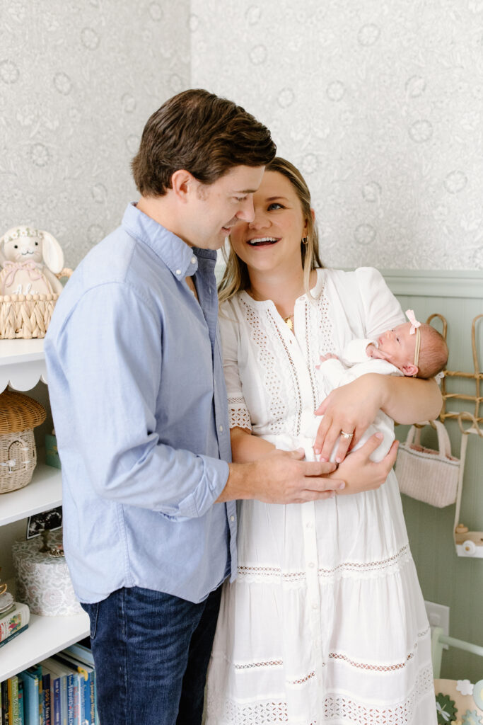 close up of parents smiling towards each other and holding baby during newborn photos in Fishers, IN