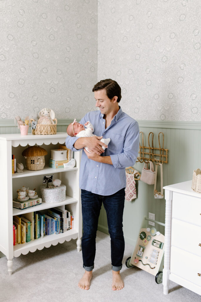 dad holding little girl in nursery during newborn photos in Fishers, IN
