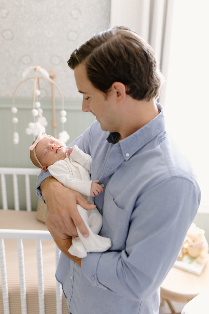 baby asleep in dad's arms while in nursery during newborn photos in Fishers, IN