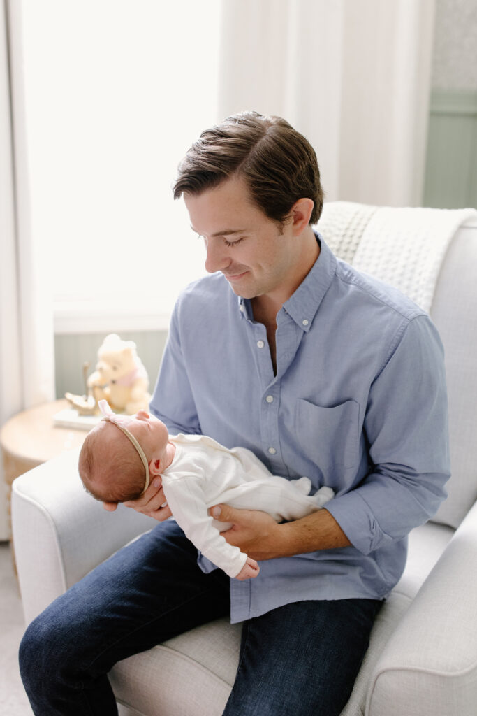 dad holding baby in rocker during newborn photos in Fishers, IN