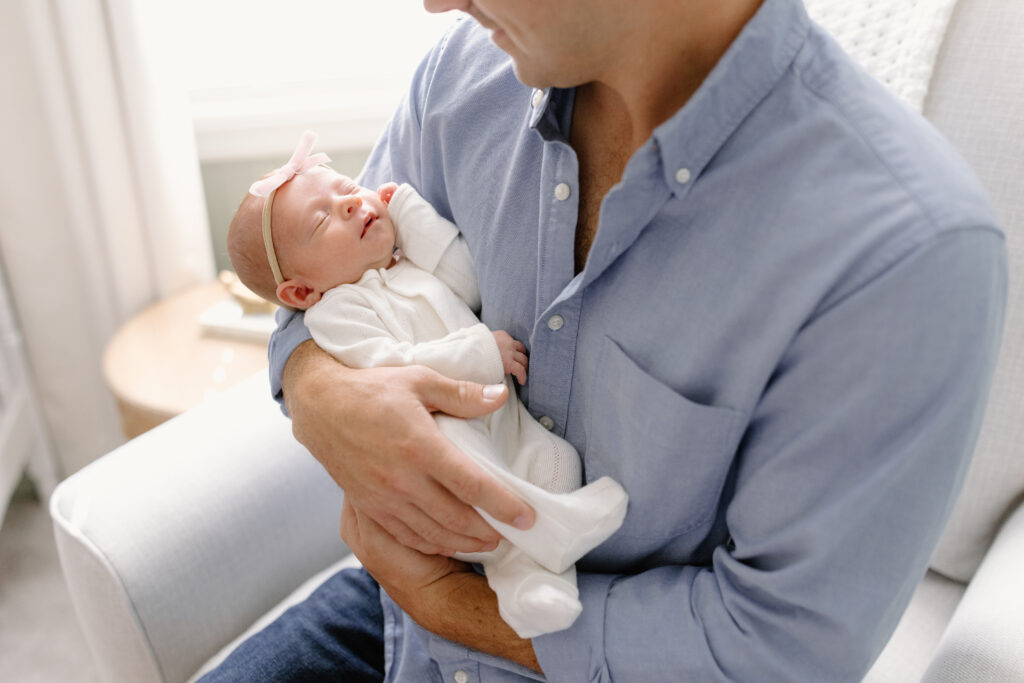 close up of dad holding baby in rocker during newborn photos in Fishers, IN
