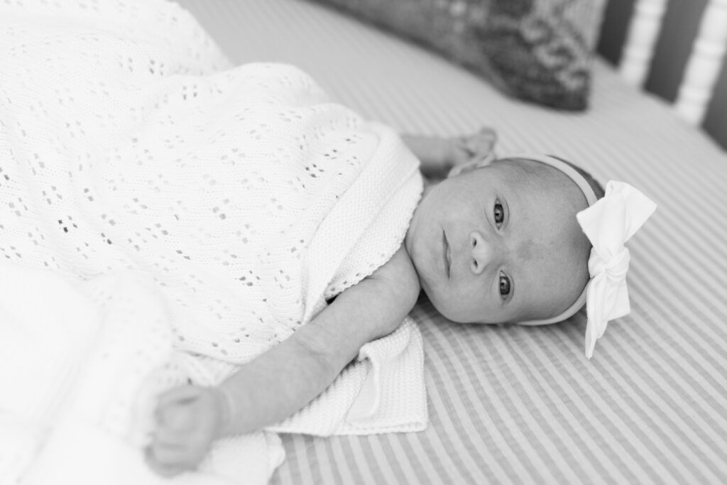 black and white of baby in crib during newborn photos in Fishers, IN