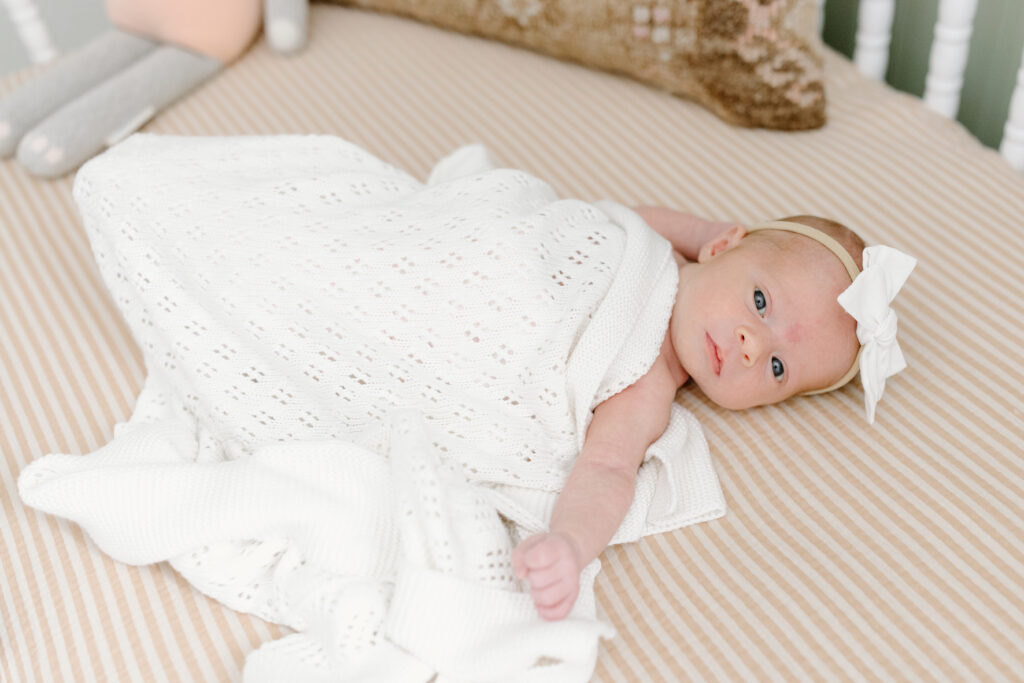 little girl lying in crib during newborn photos in Fishers, IN