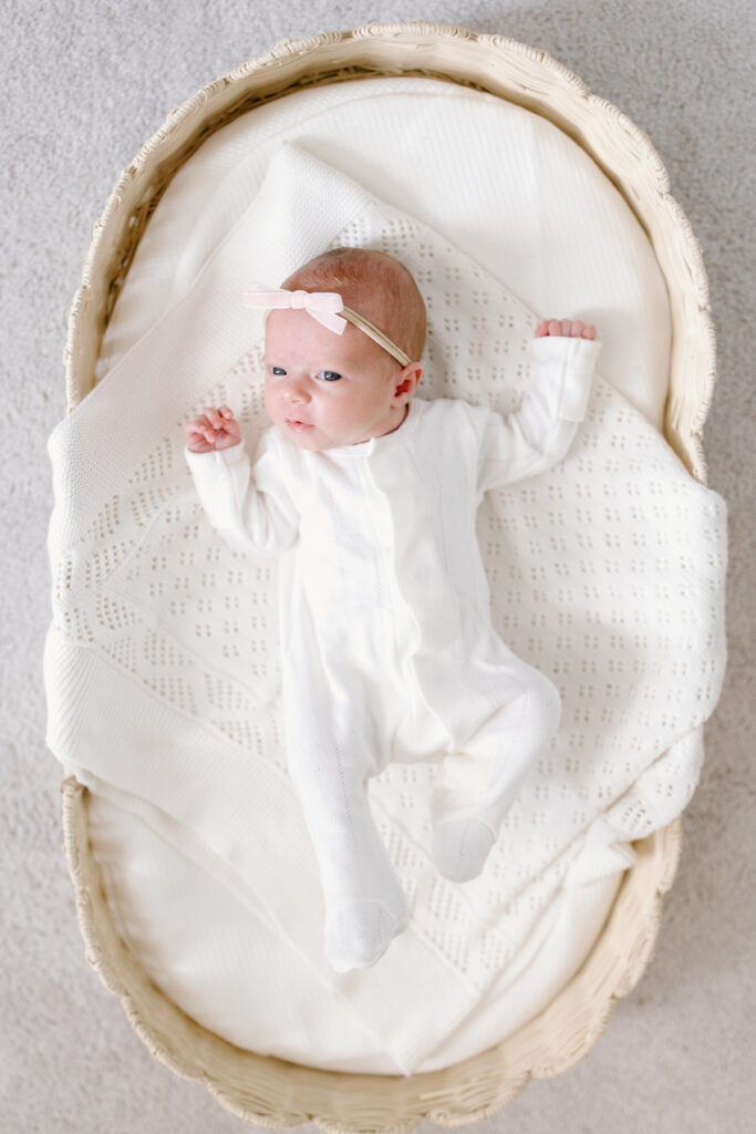 baby laying in basket and looking towards the camera during newborn photos in Fishers, IN