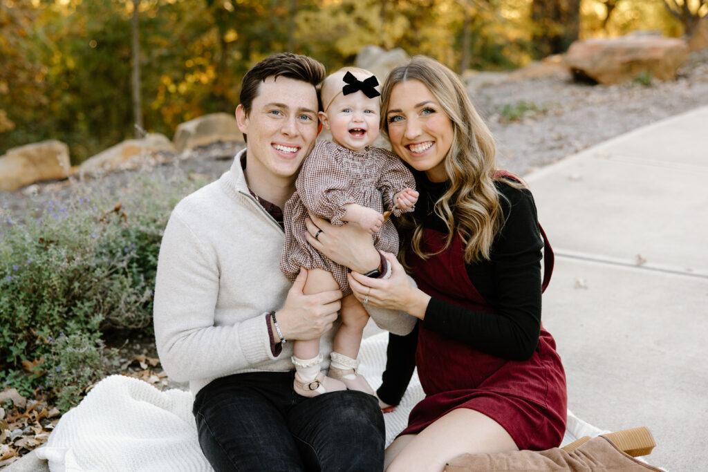 Family of three smiling during fall mini sessions with capturing simplicity photography in Carmel, IN