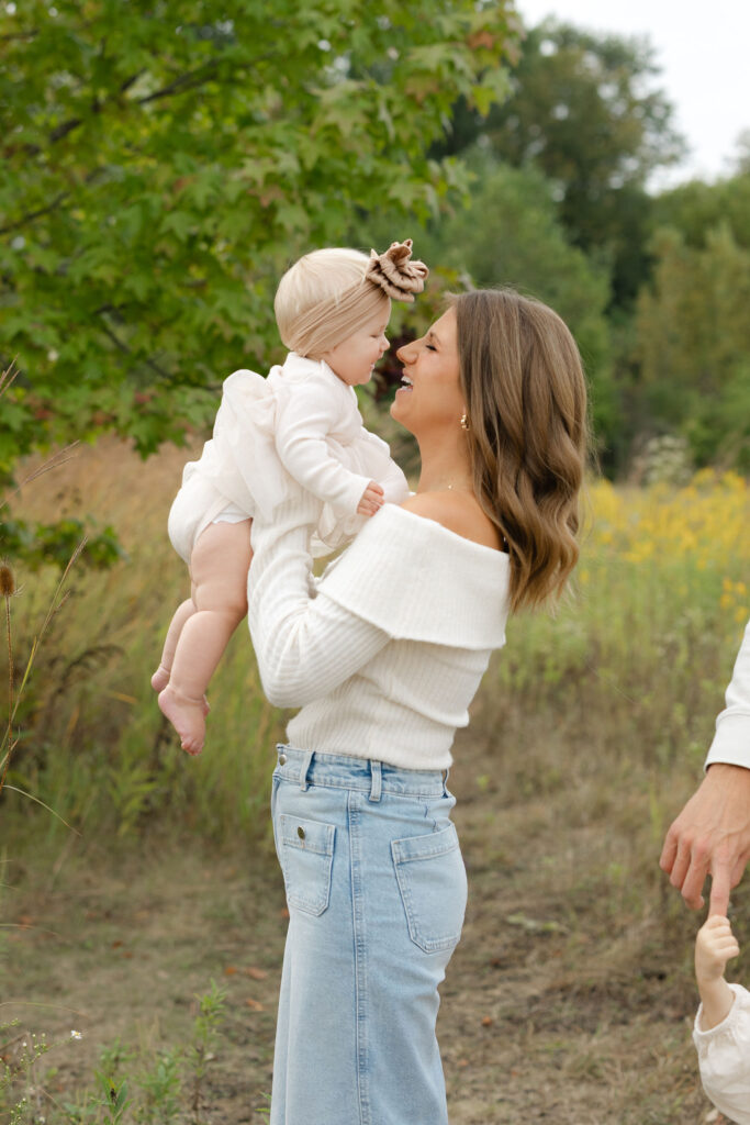 Mom lifting daughter during fall family photos at West Park in with Capturing Simplicity Photography