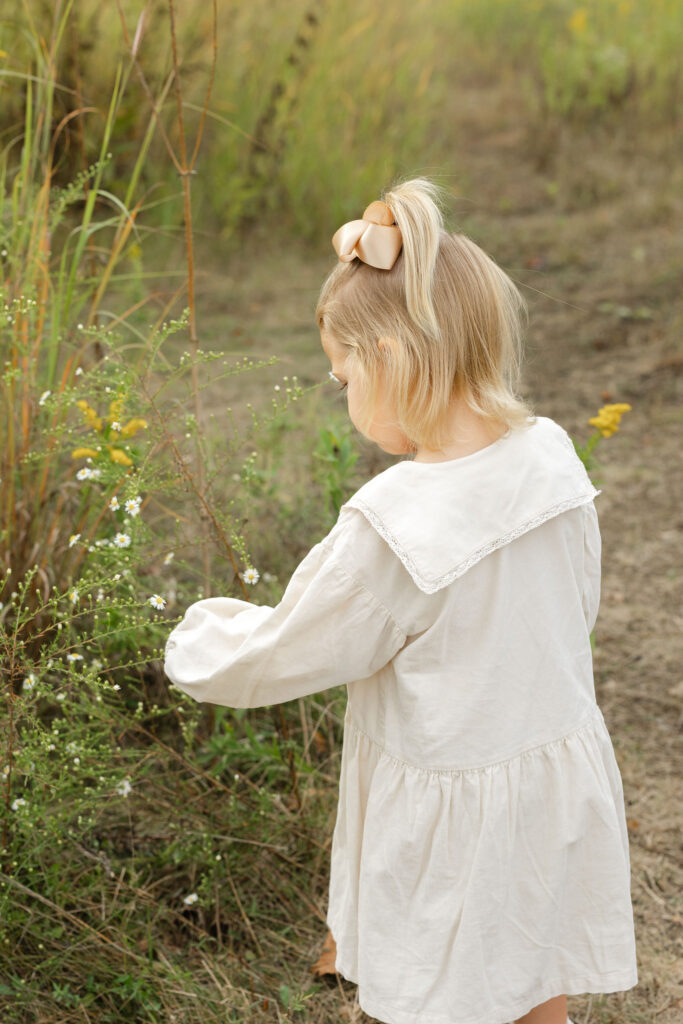 Little girl picking flowers during fall family photos at West Park in with Capturing Simplicity Photography