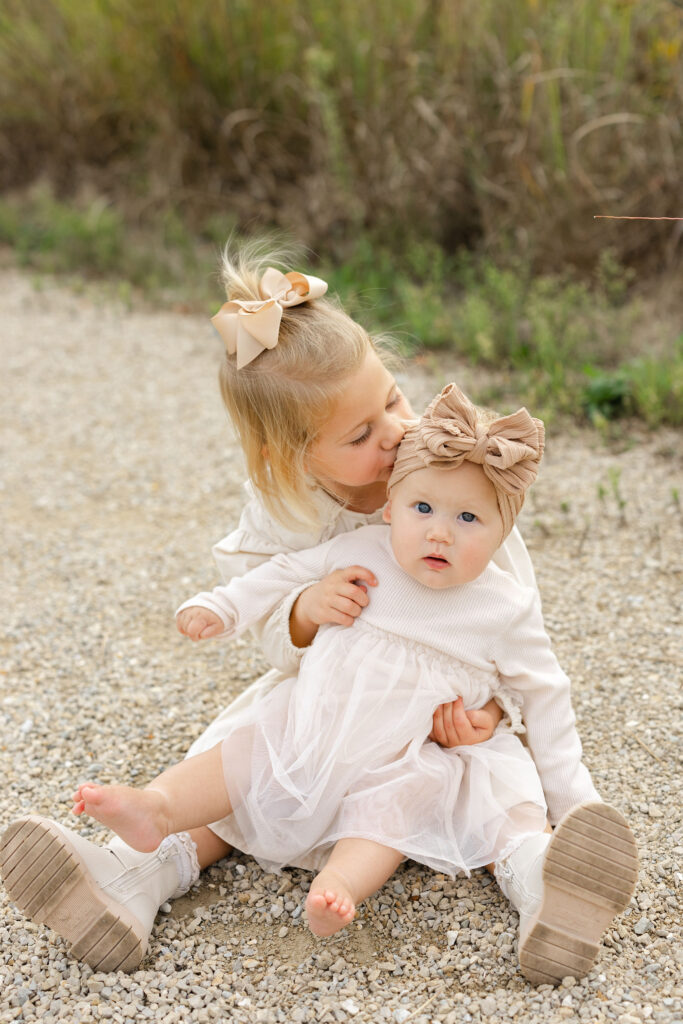 Big sister kissing little sister during fall family photos at West Park in with Capturing Simplicity Photography