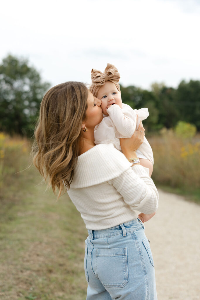 Mom kissing little girl during fall family photos at West Park in with Capturing Simplicity Photography