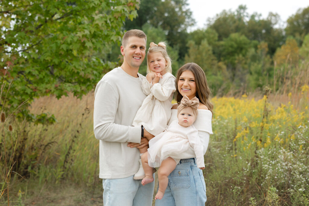 Girls smiling while held by parents during fall family photos at West Park in with Capturing Simplicity Photography