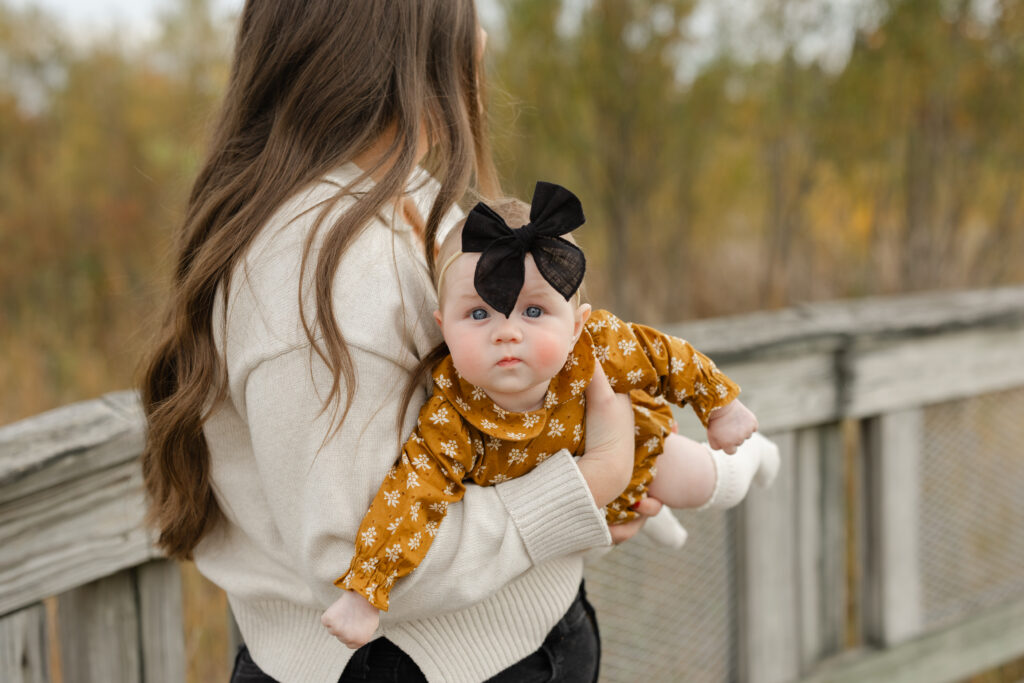 Little girl held by mom during Fall Mini Sessions at West Park with Capturing Simplicity Photography