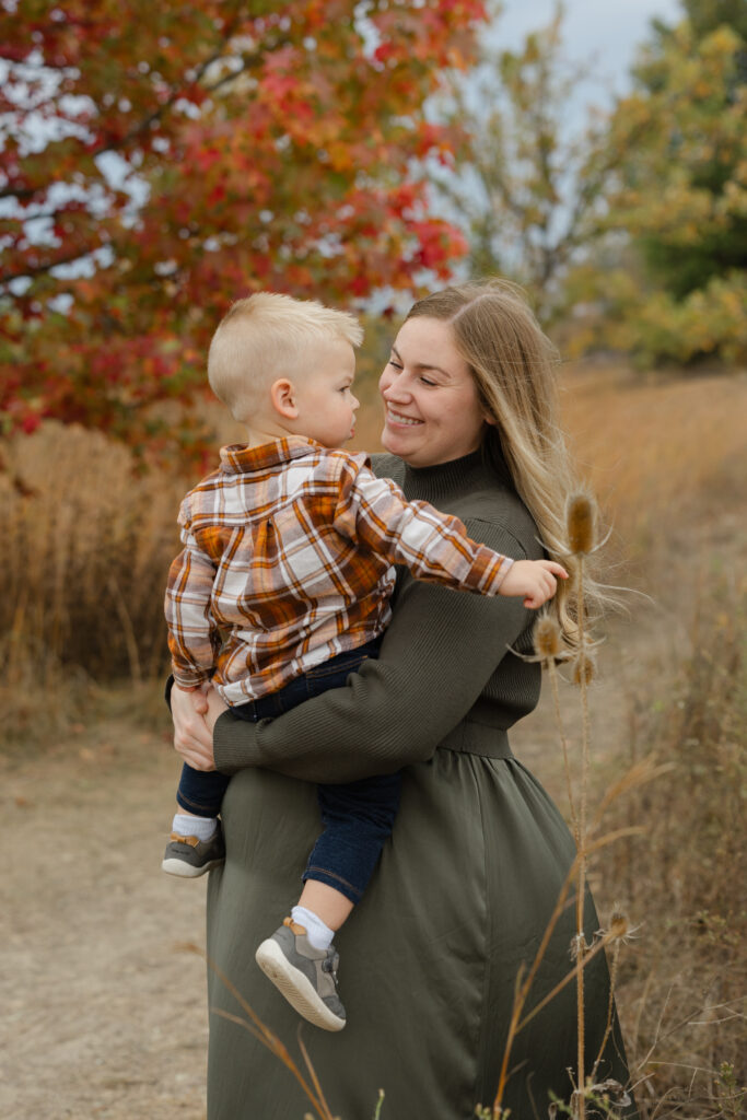 mom carrying son during Fall Mini Sessions at West Park with Capturing Simplicity Photography