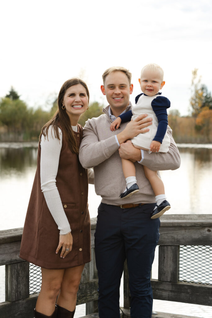 Family smiling by water during Fall Mini Sessions at West Park with Capturing Simplicity Photography