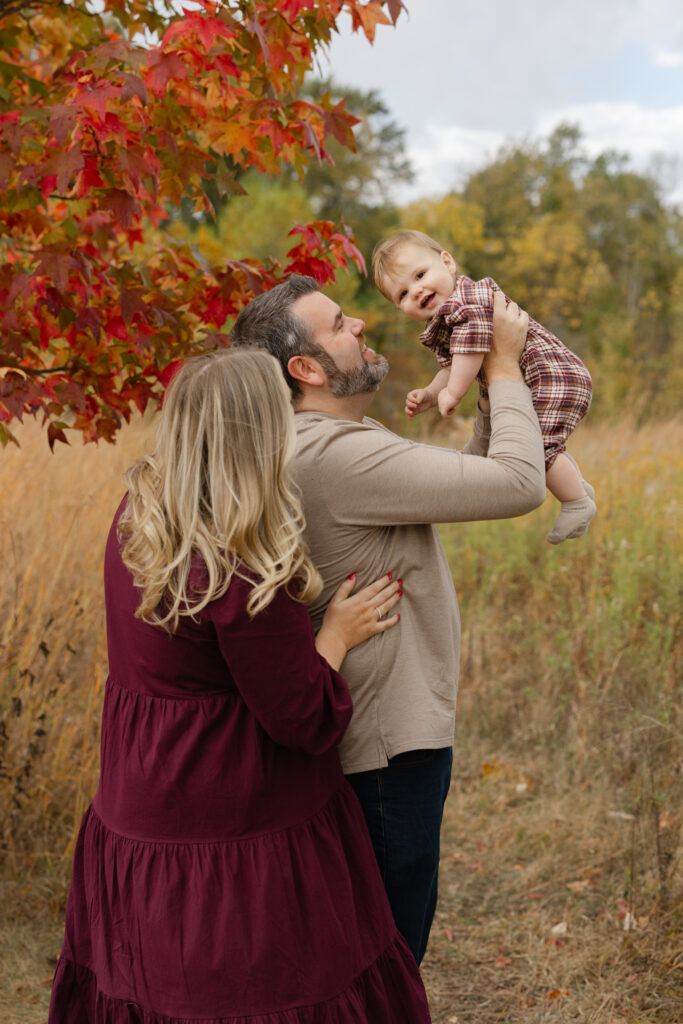 Family lifting baby boy in air during Fall Mini Sessions at West Park with Capturing Simplicity Photography