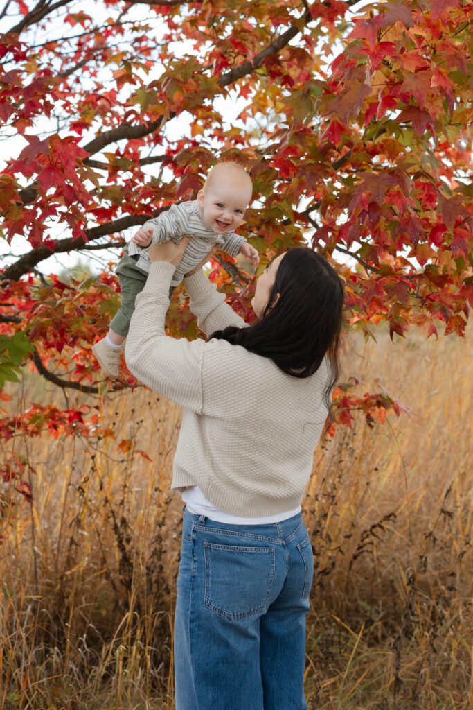 Mom lighting baby boy during Fall Mini Sessions at West Park with Capturing Simplicity Photography