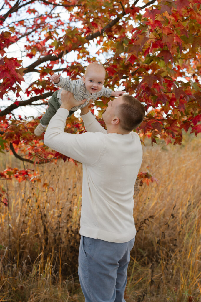 dad lifting baby boy during Fall Mini Sessions at West Park with Capturing Simplicity Photography