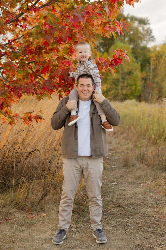 Dad lifting son on shoulders during Fall Mini Sessions at West Park with Capturing Simplicity Photography