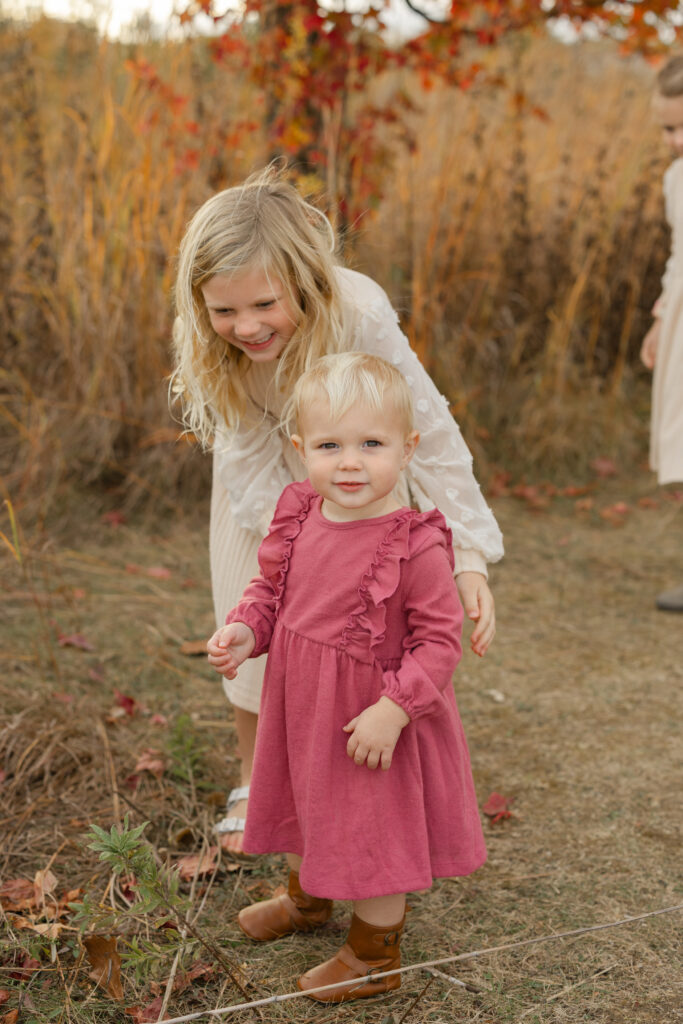 Little girl exploring with help of big sister during Fall Mini Sessions at West Park with Capturing Simplicity Photography