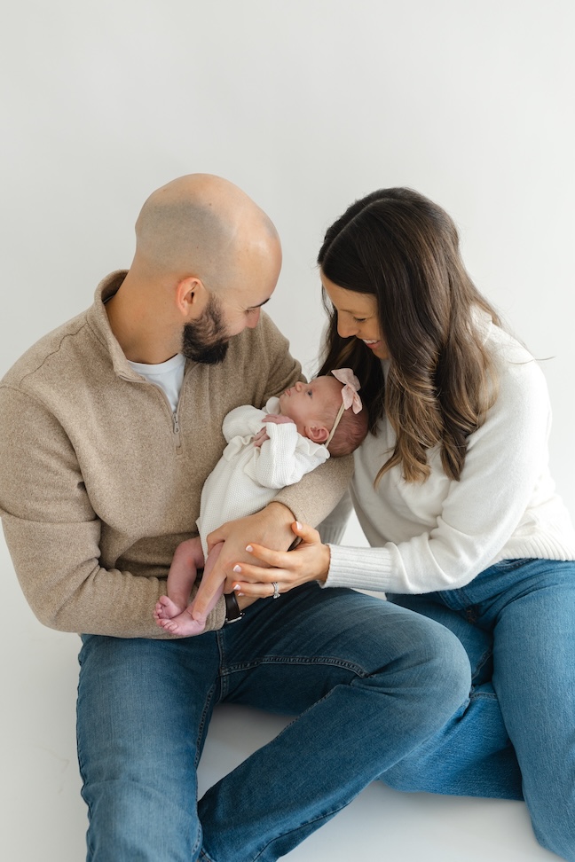 Mom and dad looking down towards newborn baby girl during newborn photos with Indianapolis Newborn Photographer Capturing Simplicity Photography