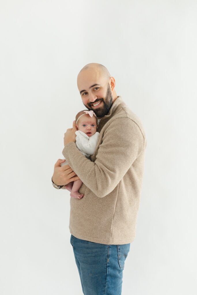 Dad snuggling baby girl into his chest during newborn photos with Indianapolis Newborn Photographer Capturing Simplicity Photography
