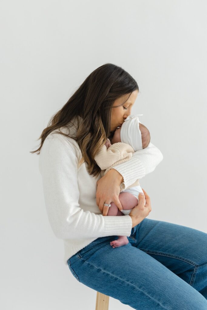 Mom kissing baby girl's forehead during newborn photos with Indianapolis Newborn Photographer Capturing Simplicity Photography