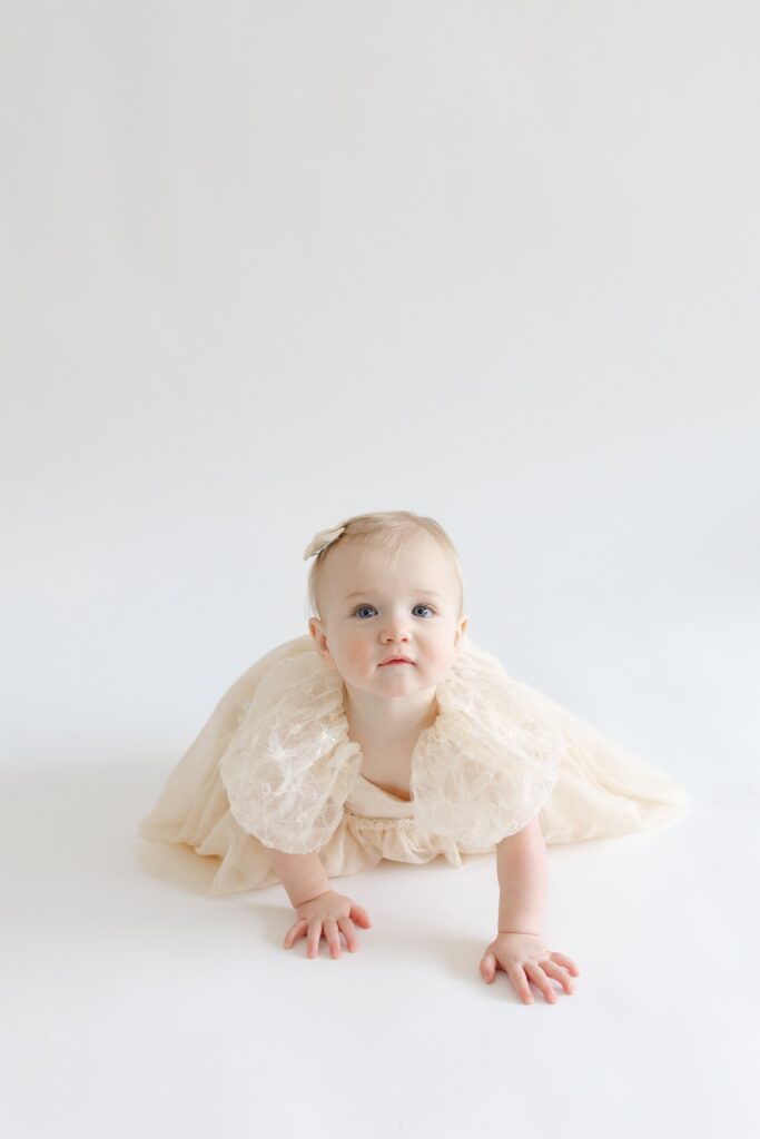 Baby girl crawling in tan dress during first birthday photos in Indianapolis with Capturing Simplicity Photography