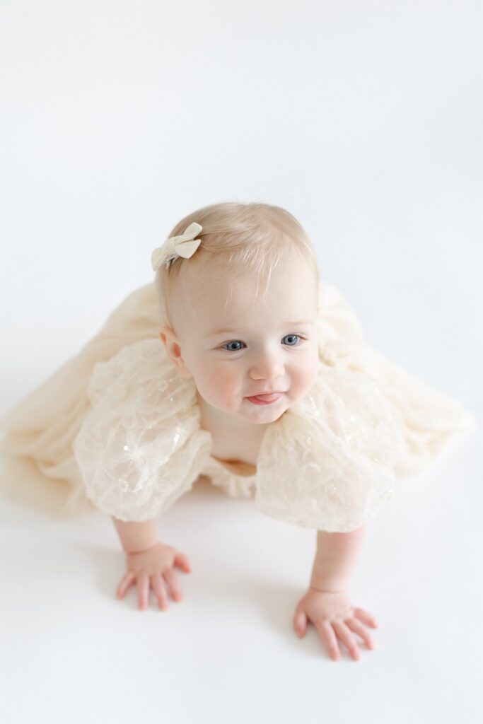 Baby girl crawling and making playful faces during first birthday photos in Indianapolis with Capturing Simplicity Photography