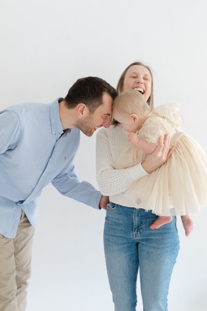 Little girl playing with mom and dad during first birthday photos in downtown Indianapolis studio with Capturing Simplicity Photography